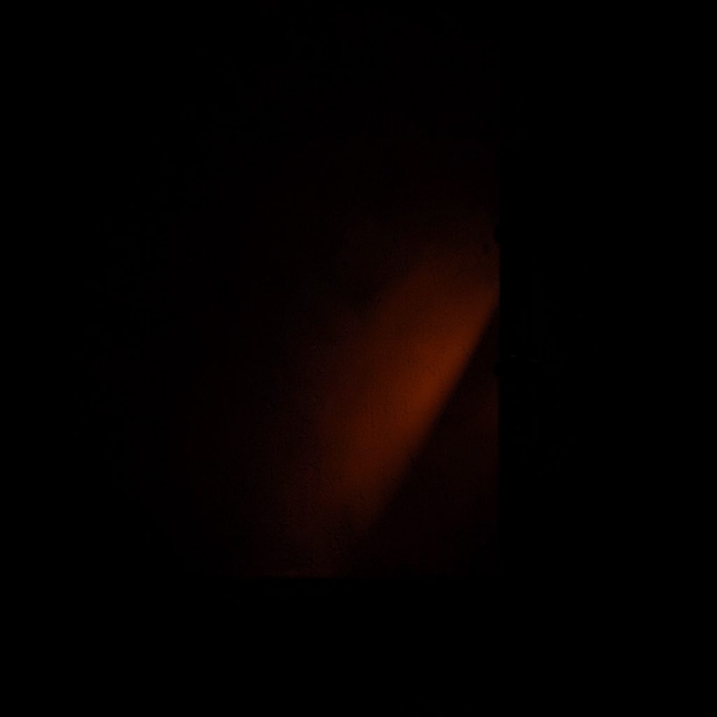 A dark minimal photograph evoking a virtual reality setup, deep shadow tones with a hint of warm orange light