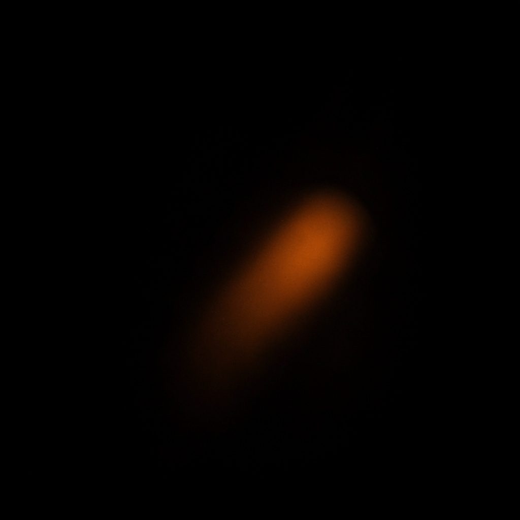 A moody dark photograph of a virtual reality controller resting on a shadowed surface with faint warm orange light